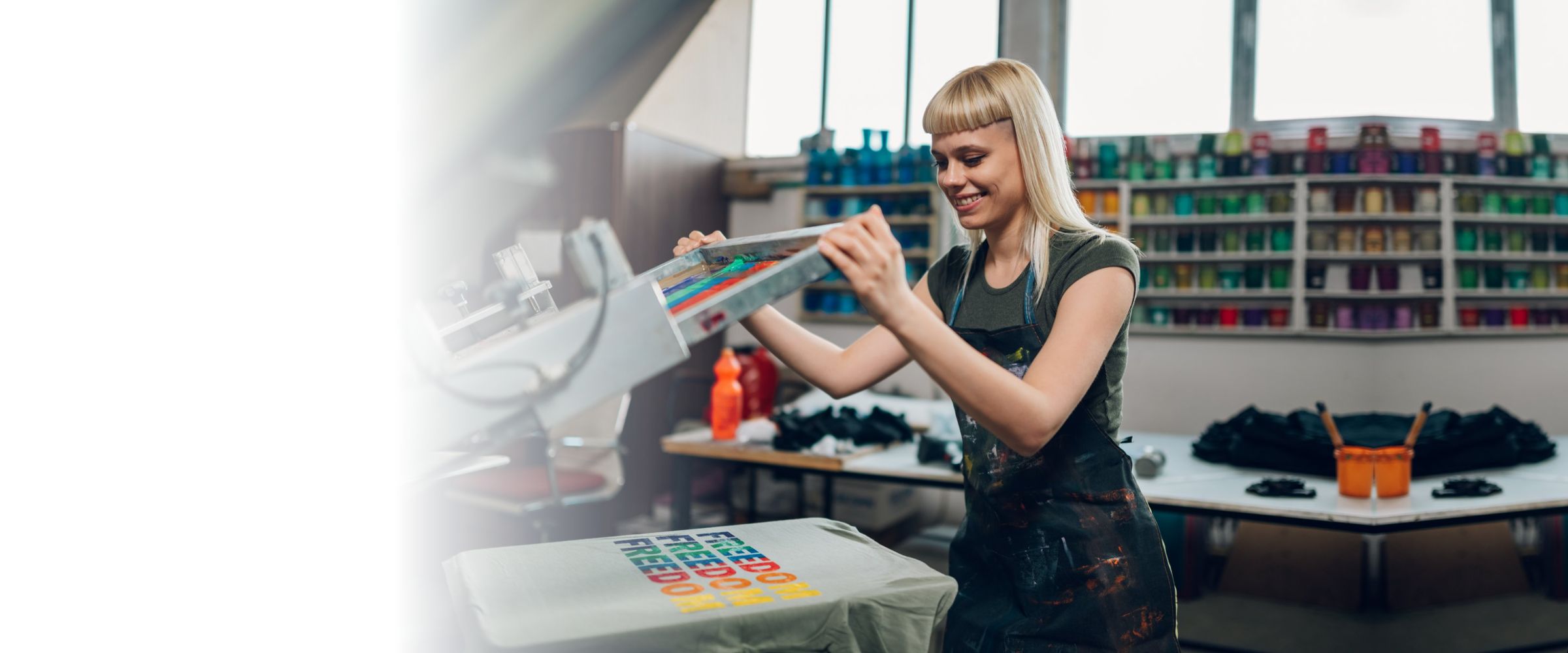 Print shop worker screen-printing a design onto a t-shirt